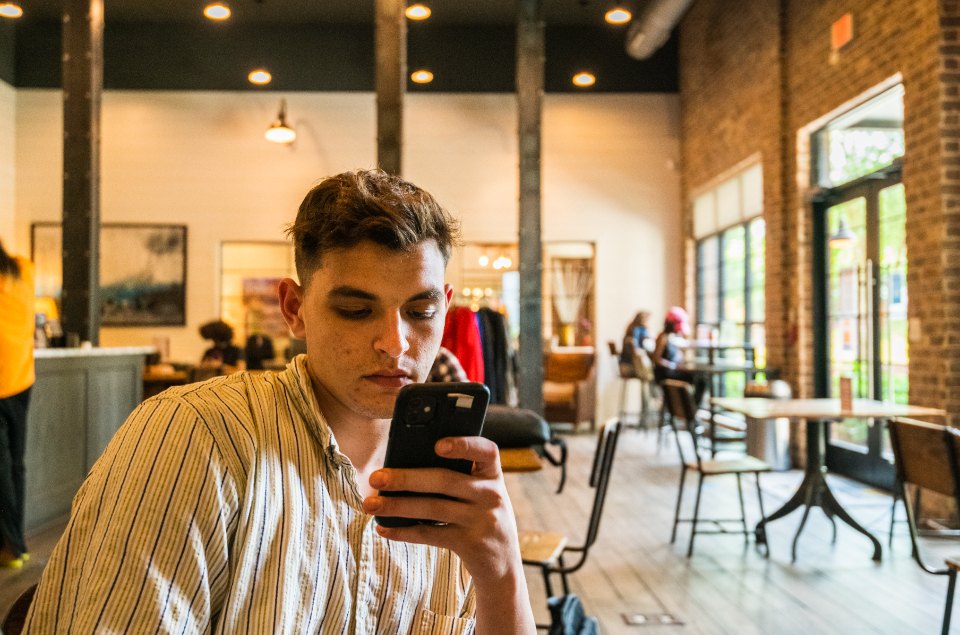 Customer checking reviews on his phone at a cafe table