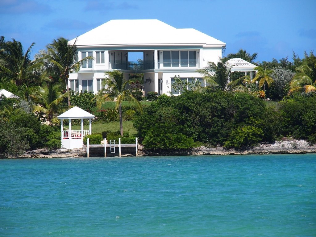 White waterfront vacation home with palm trees and turquoise water