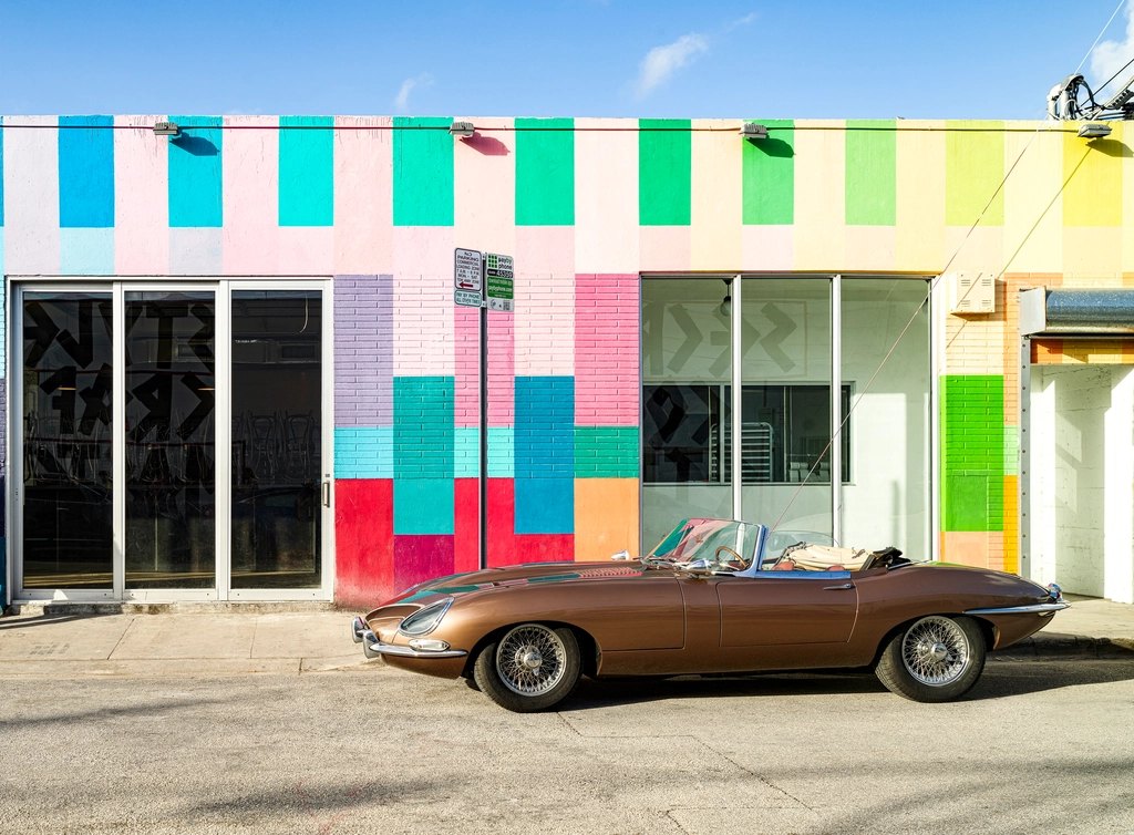 Colorful local storefront with a classic convertible parked outside