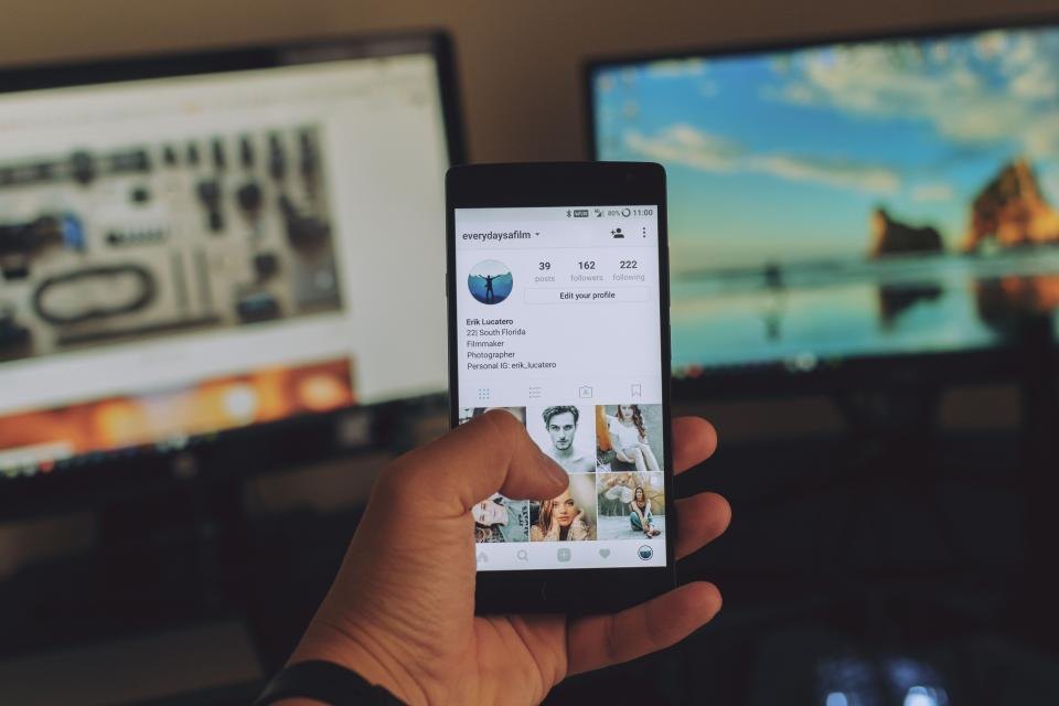 Hand holding a smartphone open to a social media feed