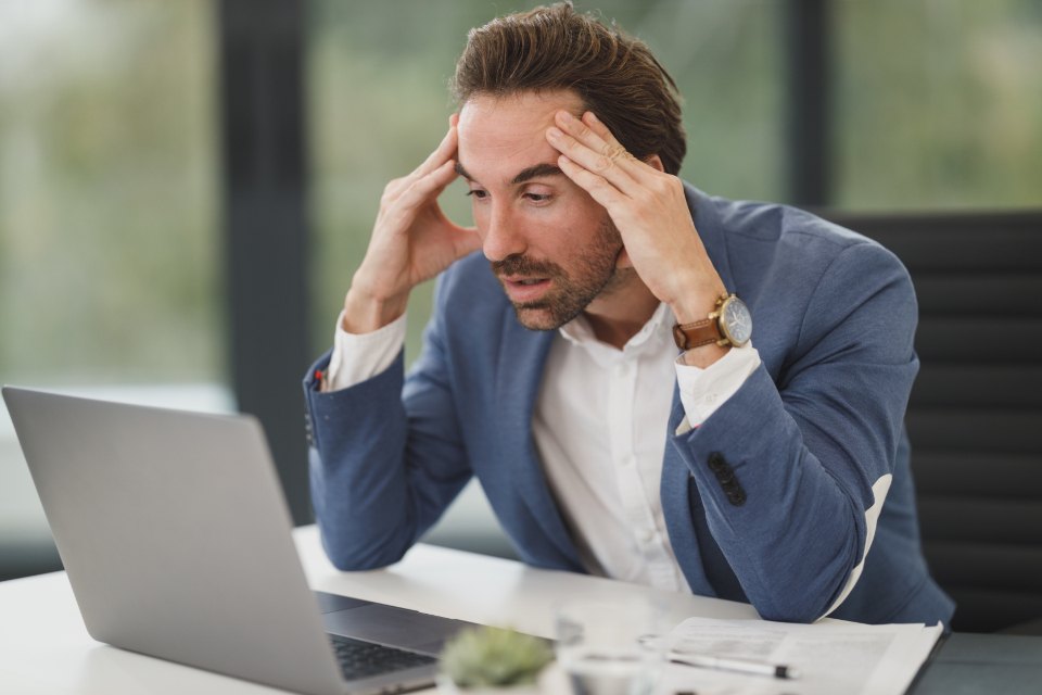 Frustrated business owner with his head in his hands at a laptop