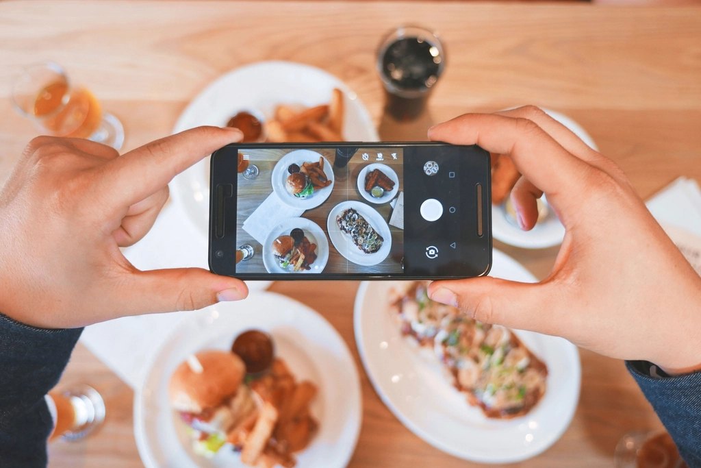 Diner photographing plates of food with a smartphone
