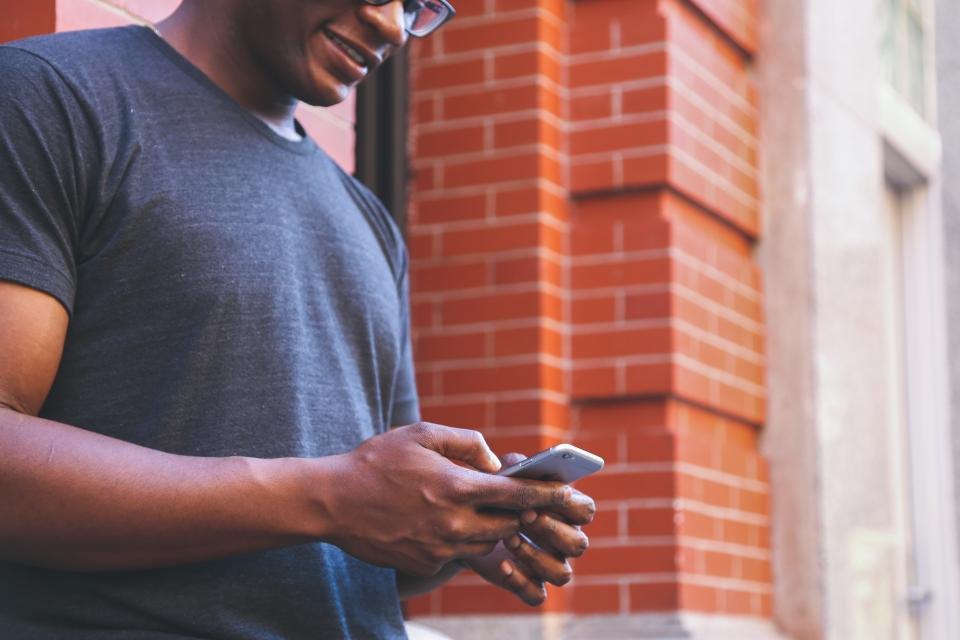 Man using a smartphone on a city sidewalk