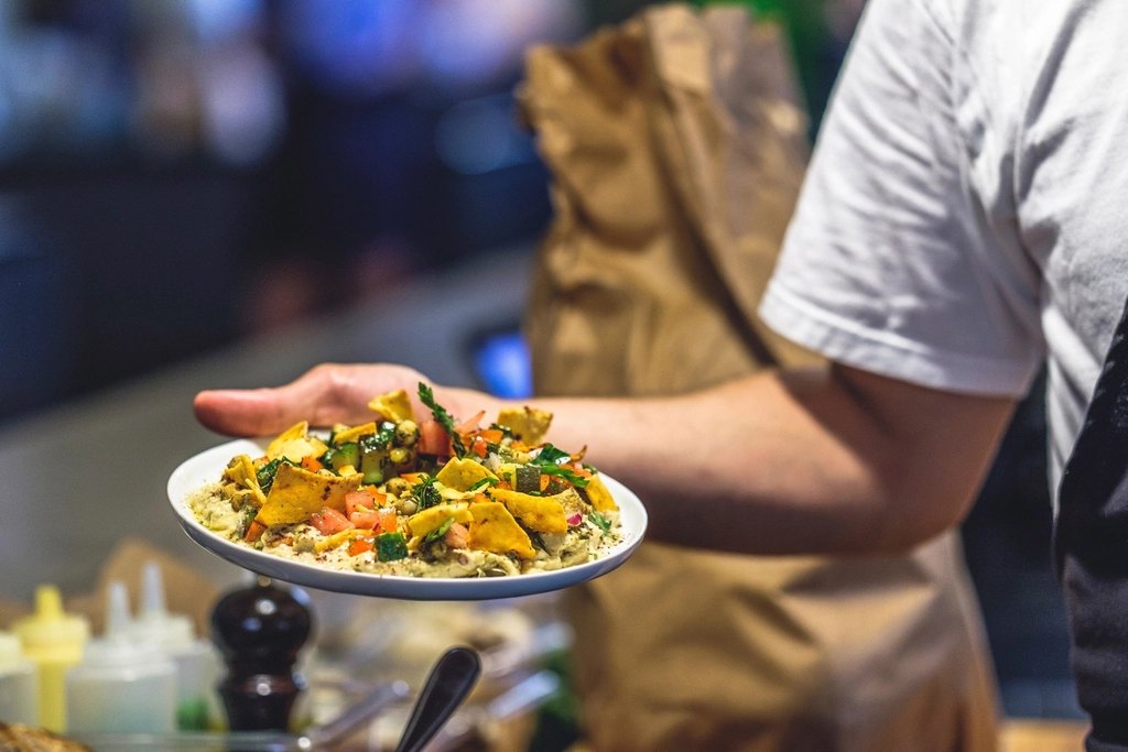 Server carrying a plate of food in a busy restaurant