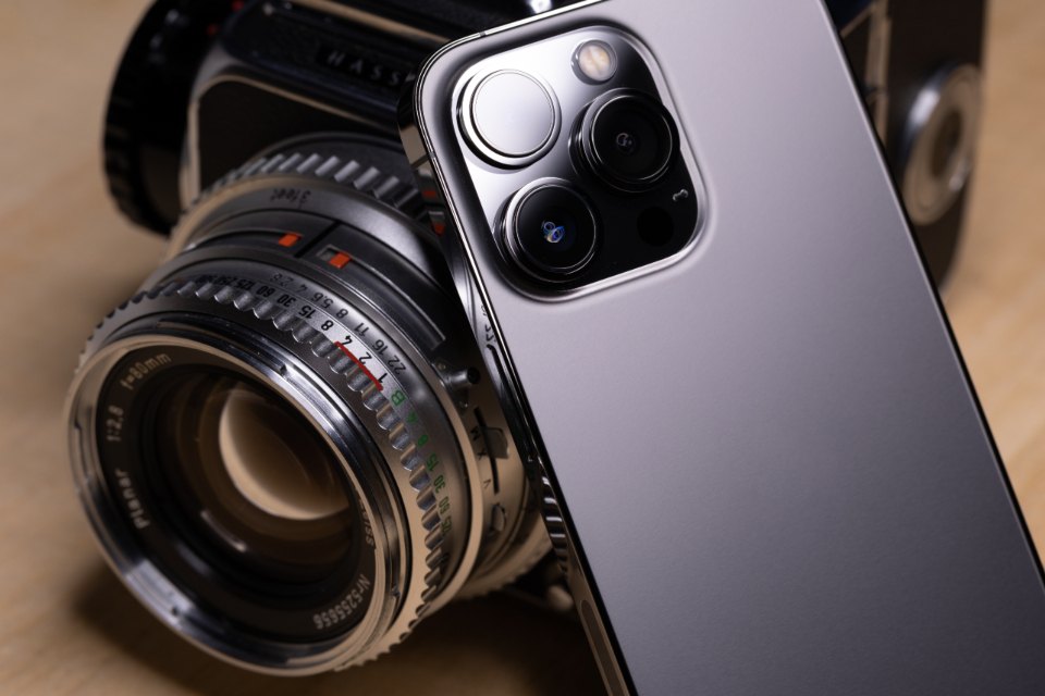 Smartphone camera beside a vintage film camera