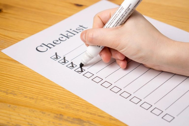Hand checking off items on a printed checklist